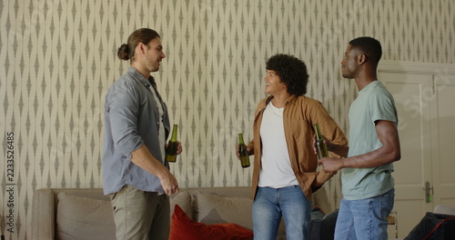 Friends celebrating with beer bottles, smiling and enjoying time together at home