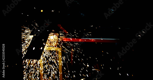 Bright sparks fly from a metal grinding process in a dark environment, creating a dramatic contrast
