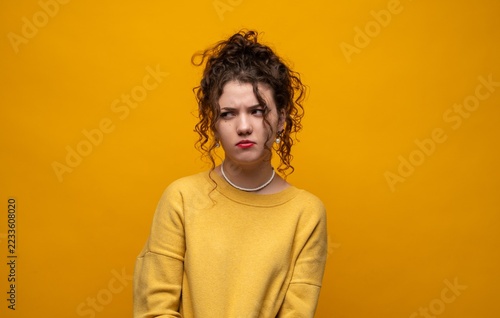 Obraz na plátně Young woman expressing annoyance and skepticism, looking to the side with a frow