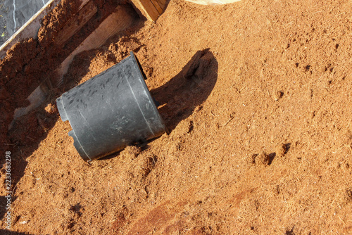 Obraz na plátně Coconut coir substrate filling a wooden bin with an empty black plastic nursery pot lying on its side, ready for gardening and planting