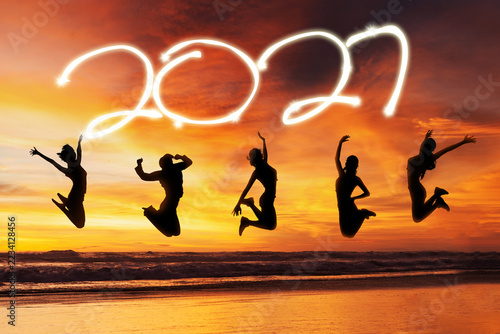 Silhouettes of People Jumping on Beach under Glowing 2027 Text at Sunset