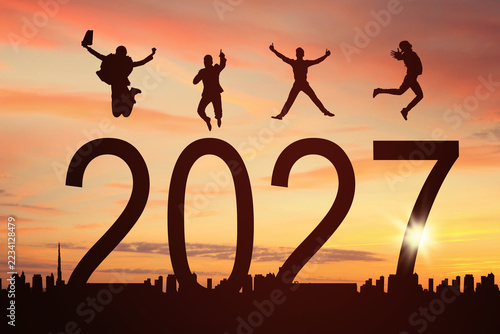Silhouettes of Business People Jumping Over 2027 Year Numbers at Sunset