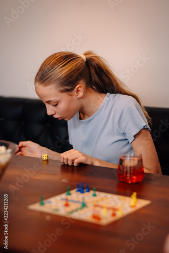 Girl blowing on dice playing board game at home