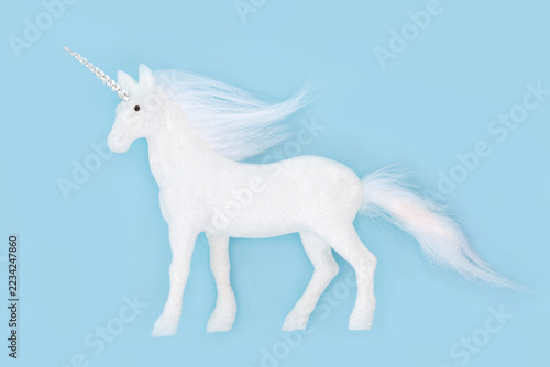 Magical unicorn Christmas tree frosted decoration on pastel blue background. Legendary mythical white creature for festive greeting card. 