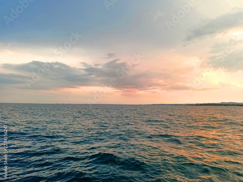 Obraz na plátně A night panorama of the boundless sea surface, reflecting the fiery, rainbow-like colors of a sunset