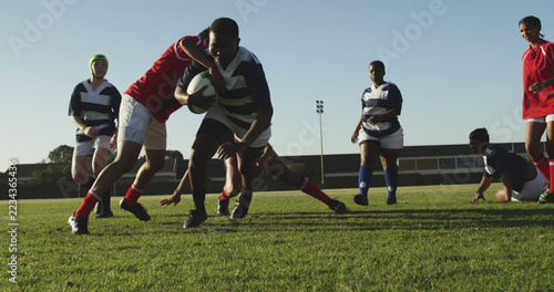Diverse teenagers play rugby on an outdoor field