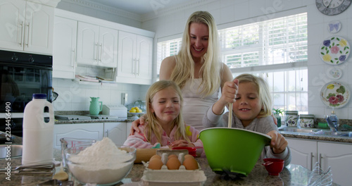 Happy caucasian mother with son and daughter preparing dough in kitchen