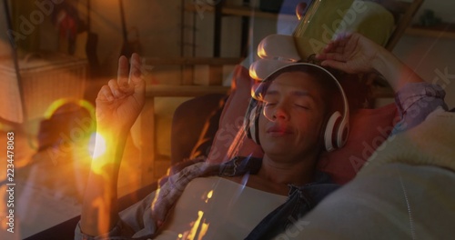 Obraz na plátně Listening woman on sofa holding tablet above head at home, wearing headphones, c