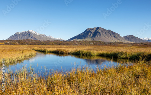 Snow covered mountain view in the Borgarbyggd region of western Iceland, as seen from the Route One ring road near Fiflholt. Wetlands and autumn colours with clear blue sky.
