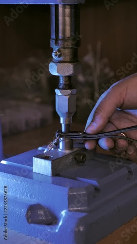Close up of leather artisan hands installing rivet on leather strap using manual press machine in workshop. Handcrafted leather accessories, artisan craftsmanship, leatherworking and maker concept