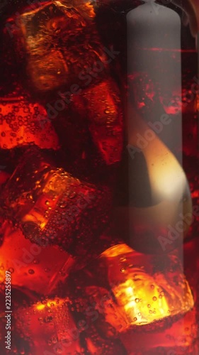 A close-up of a refreshing summer cocktail. Ice cubes swirl slowly in the glass, and gas bubbles rise to the surface