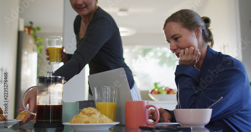 Caucasian lesbian couple having a imagecall on laptop while having breakfast at home