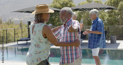 Happy african american senior couple hugging at swimming pool