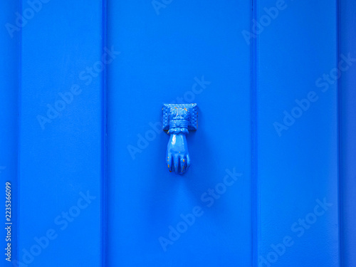 Fragment of wooden door, ornate metal doorknob or styled metal handle in Porto, Portugal. Close-up. Old wall with blue paint, brass knocker or vintage door handle. Abstract textured surface for design