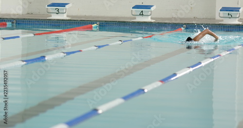 Swimming in lane, athlete practicing freestyle stroke in indoor pool, copy space