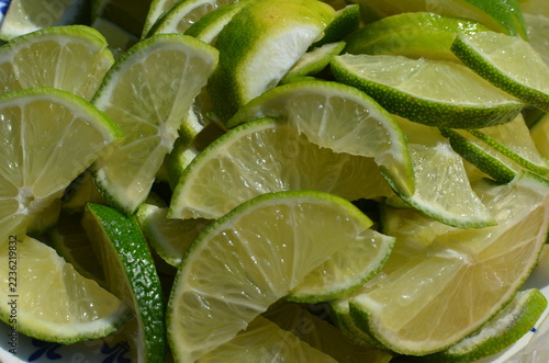 Obraz na plátně Fresh juicy green lime slices cut into wedges, top view close up, citrus fruit b