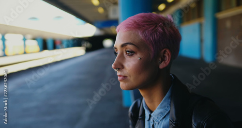 Young Caucasian woman stands at a train station, with copy space