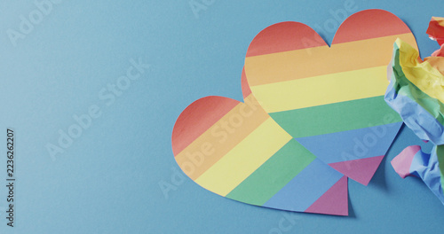 Image of rainbow hearts over blue background with copy space