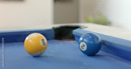 9 and 2 billiard balls are sitting on blue-felt pool table near corner pocket, reflections glinting
