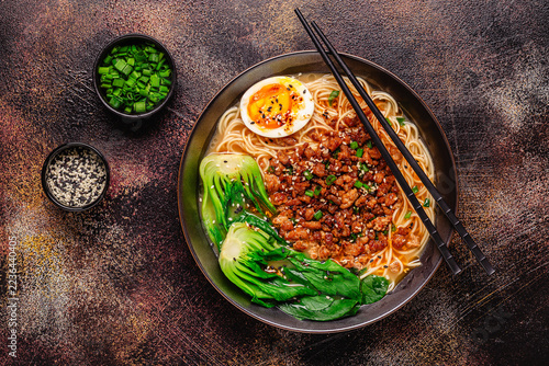 A bowl of noodles with minced meat, egg, and bok choy.