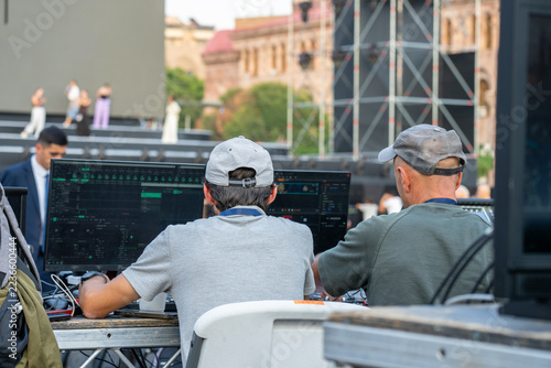 Two men are working at technical equipment, likely controlling the sound or lighting.