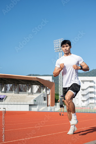 Fotografie Asian Male Athlete Sprinting Along Outdoor Stadium Running Track.