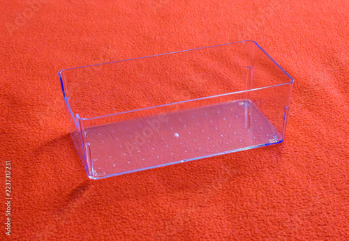 Clear plastic rectangular container resting on an orange fabric surface