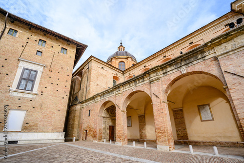 Arcades of Palazzo Ducale with the dome of Urbino Cathedral rising above the historic center of Urbino, Marche, Italy