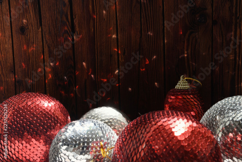 Red and silver Christmas balls with shiny sequins on a wood table. Festive holiday decor.