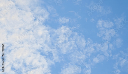 Clouds in the blue sky during the day with a bright atmosphere visible above a landscape