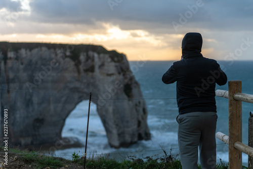 Touriste contemplant les falaises et l’arche naturelle d’Étretat en Normandie