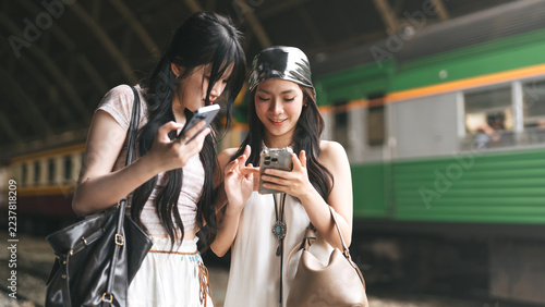 Two young asian woman gen Z content creator arrival at train terminal station friendship local travel trip in Bangkok, Thailand